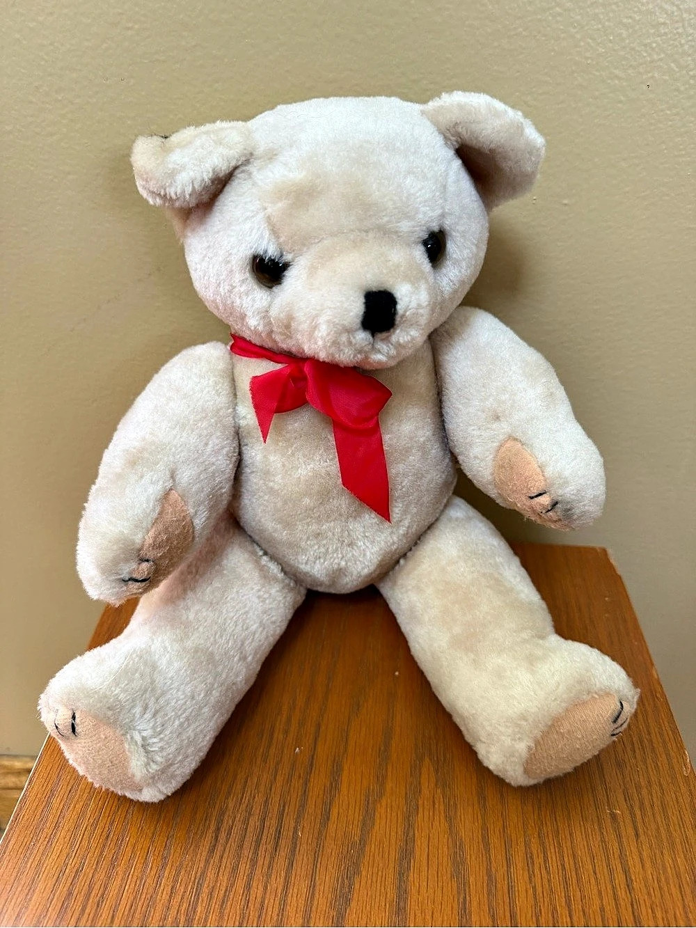 vintage jointed teddy bear with black eyes, a red satin bow around its neck, and